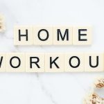 Stylish letter tiles spelling 'Home Workout' on a clean marble background with floral accents.